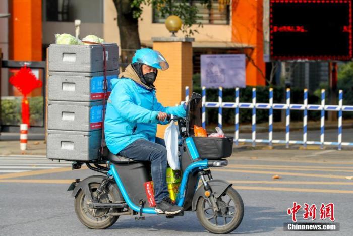 资料图：2月5日，湖北武汉经济技术开发区，一名送货的配送员正在忙碌工作。/p中新社记者 张畅 摄