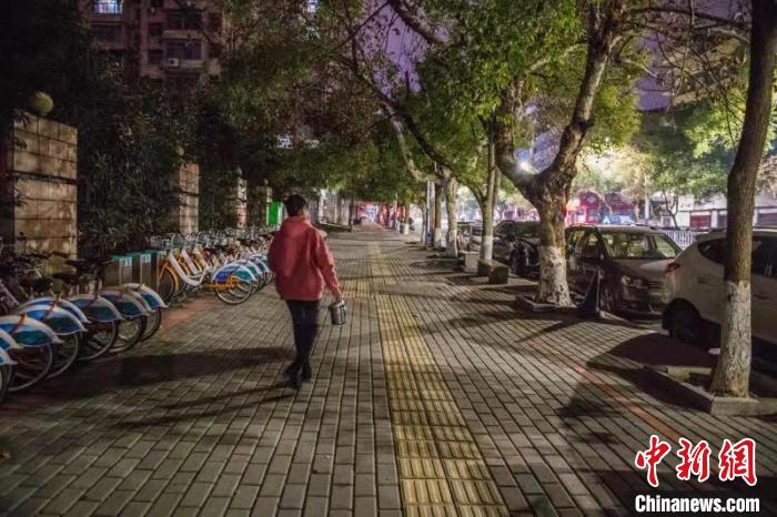 深夜，章雅琼领着饭盒行走在空旷寂静的街道。　陈东 摄